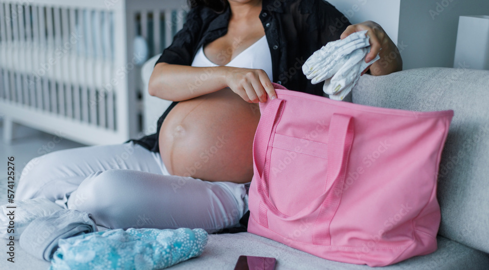 Pregnancy hospital bag. Pregnant woman preparing hospital bag for birth for  mom and baby. Expectant mother packing diapers, baby clothing etc  Stock-Foto | Adobe Stock