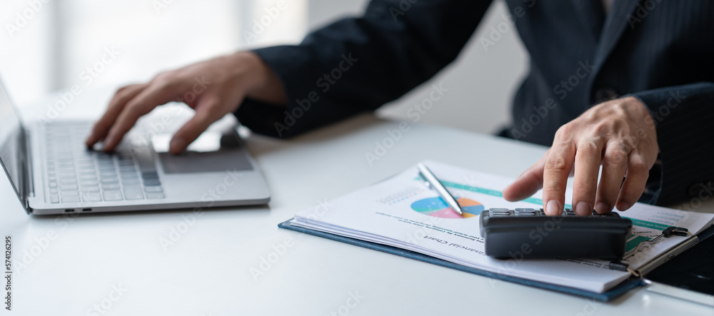 Young Asian businessman examining chart analyzing documents Financial data graph showing investment income in real estate business in office accounting management concept. Young Asian businessman examining chart analyzing documents Financial data graph showing investment income in real estate business in office accounting management concept.