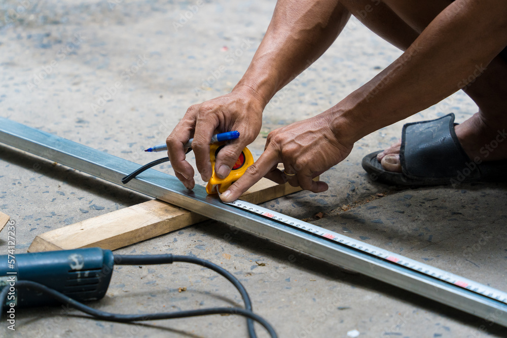 Close-up of man's hand using iron cutter in the workplace, fastening the iron canopy frame with spark Close-up of man's hand using iron cutter in the workplace, fastening the iron canopy frame with spark
