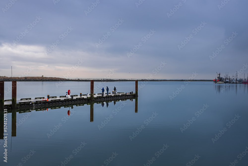 Men fishing on a pier in a early morning. Man with a fishing rod on a river.