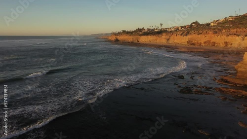 Wallpaper Mural Stunning drone shot follows the rugged cliffs during sunset, with the waves crashing below and the sun casting a warm, golden glow over the dramatic coastline Torontodigital.ca