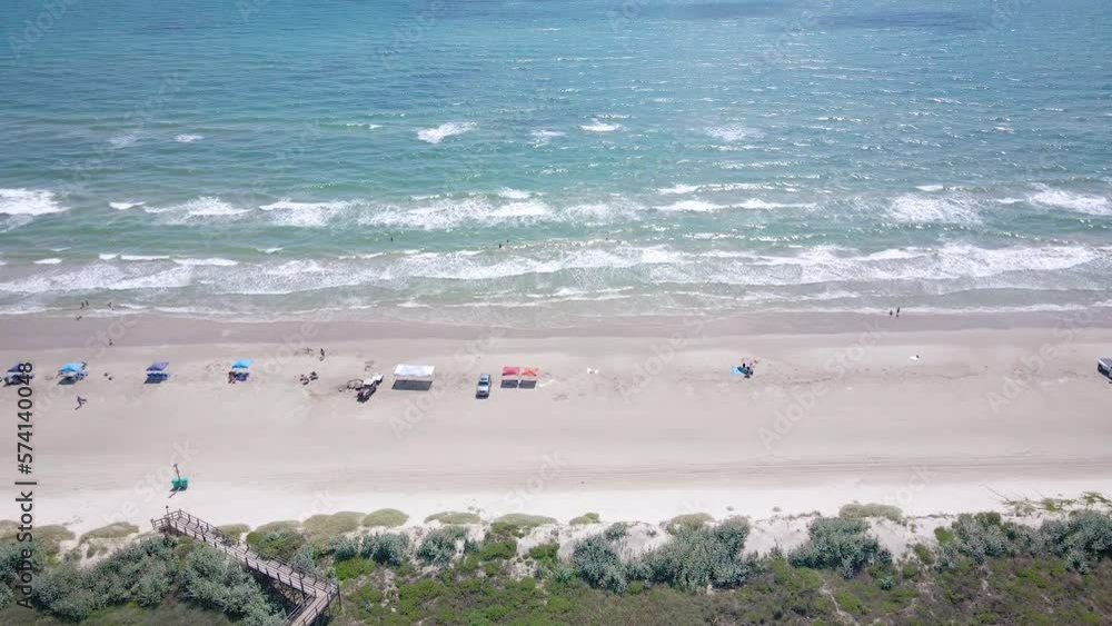 Smooth drone shot of the Texas beach on the coast in the island town of Port Aransas near the famous resort Port Royal. Waves crash on the shore and the sun gleams in the bright blue water. Smooth drone shot of the Texas beach on the coast in the island town of Port Aransas near the famous resort Port Royal. Waves crash on the shore and the sun gleams in the bright blue water.