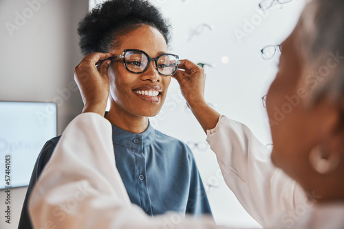 Glasses check, black woman and customer with store worker and optician looking at lense. Eye consulting, smile and eyewear assessment in a frame shop for vision test and prescription exam for eyes photo