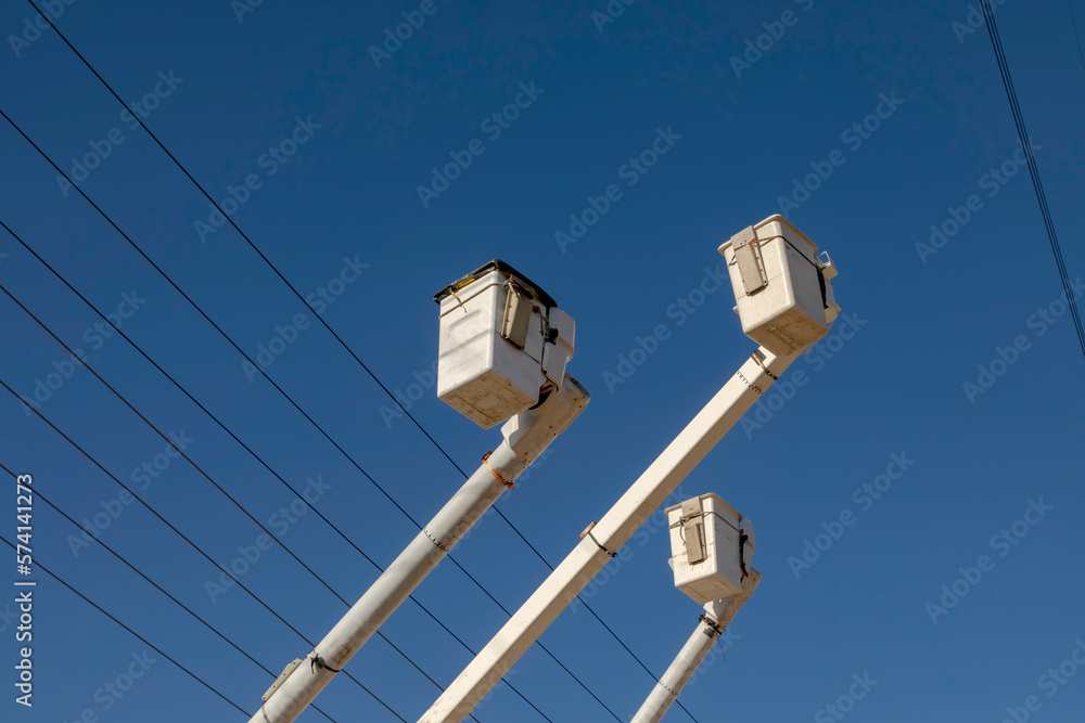 Manlift boom arms for utility work or trtee trimming against a blue sky Manlift boom arms for utility work or trtee trimming against a blue sky