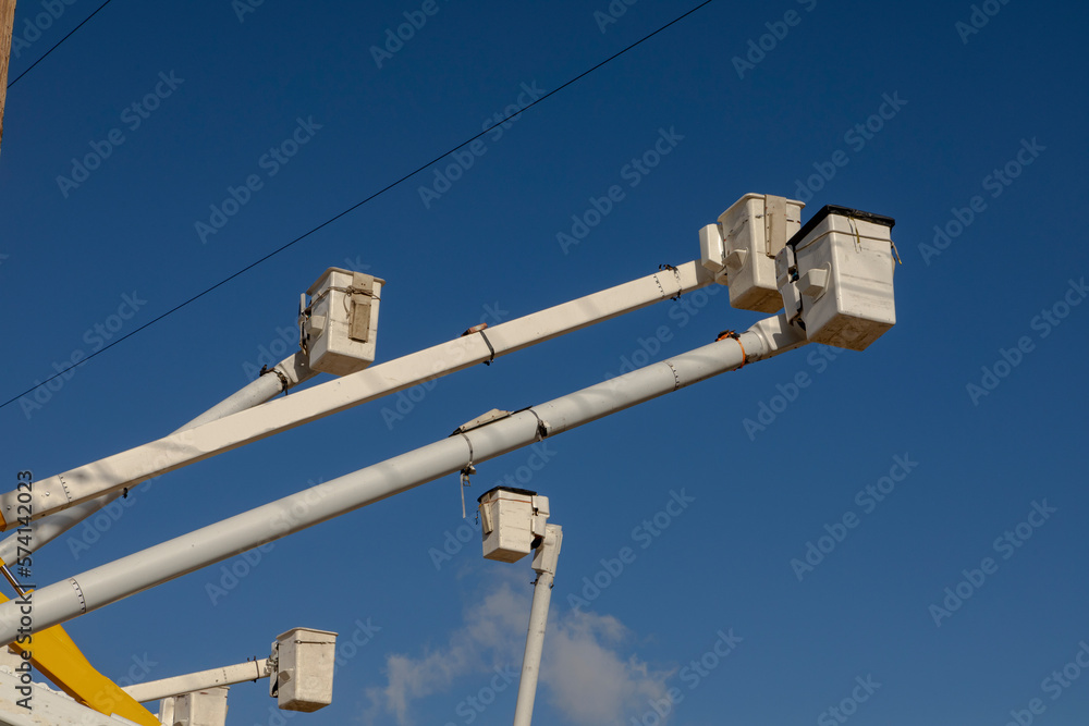Manlift boom arms for utility work or trtee trimming against a blue sky Manlift boom arms for utility work or trtee trimming against a blue sky