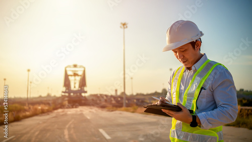 Asian engineer with hardhat using tablet pc computer inspecting and working at construction site