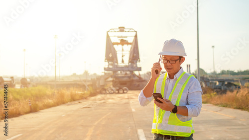 Engineer talking on walkie-talkie and using smart phone for working at construction site