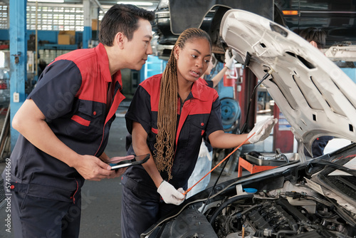 Slika na platnu Male professional automotive supervisor advises and inspects Black female mechanic worker about liquid engine oil at car garage, service maintenance, and fixing specialist occupations auto industry