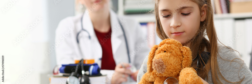 Little girl child holding toy and stethoscope at reception of pediatrician Little girl child holding toy and stethoscope at reception of pediatrician