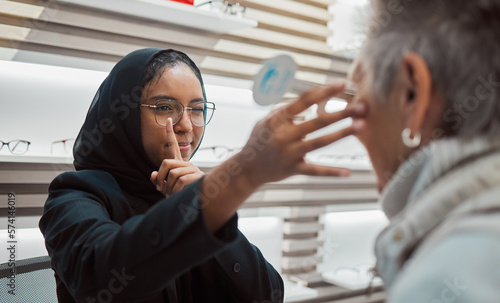 Optometry, vision and eye test with an islamic woman optician working to diagnose a customer. Doctor, optometrist and eyecare with a muslim female testing a client for prescription lenses in a clinic photo