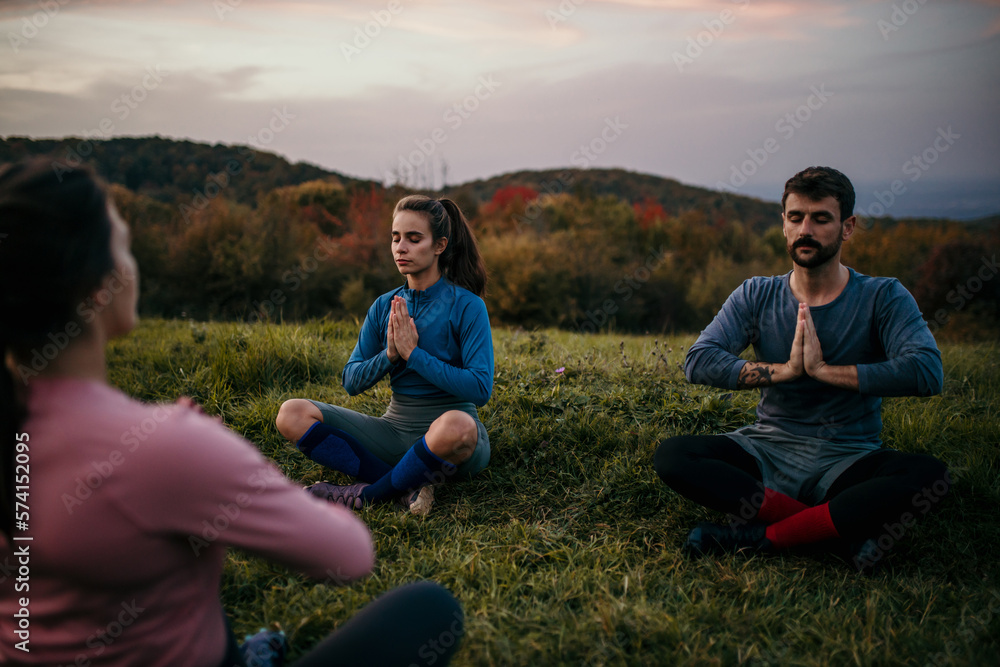 Group of friends spending a late afternoon, practicing yoga. Shot of an attractive group of people practicing yoga outdoors. 