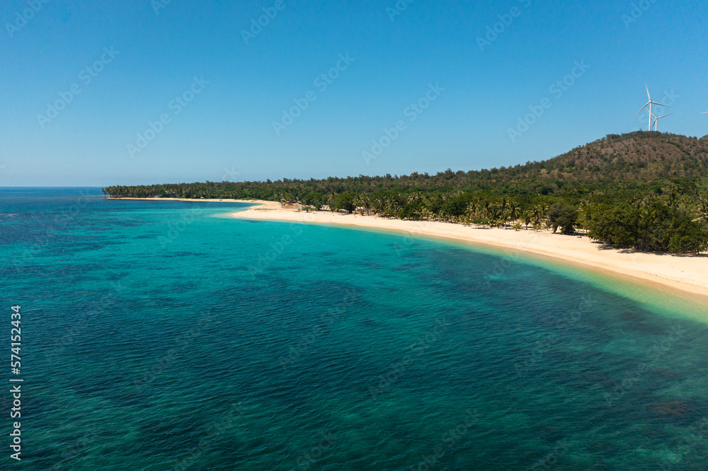 A tropical beach with palm trees and a blue ocean. Pagudpud, Ilocos Norte, Philippines.