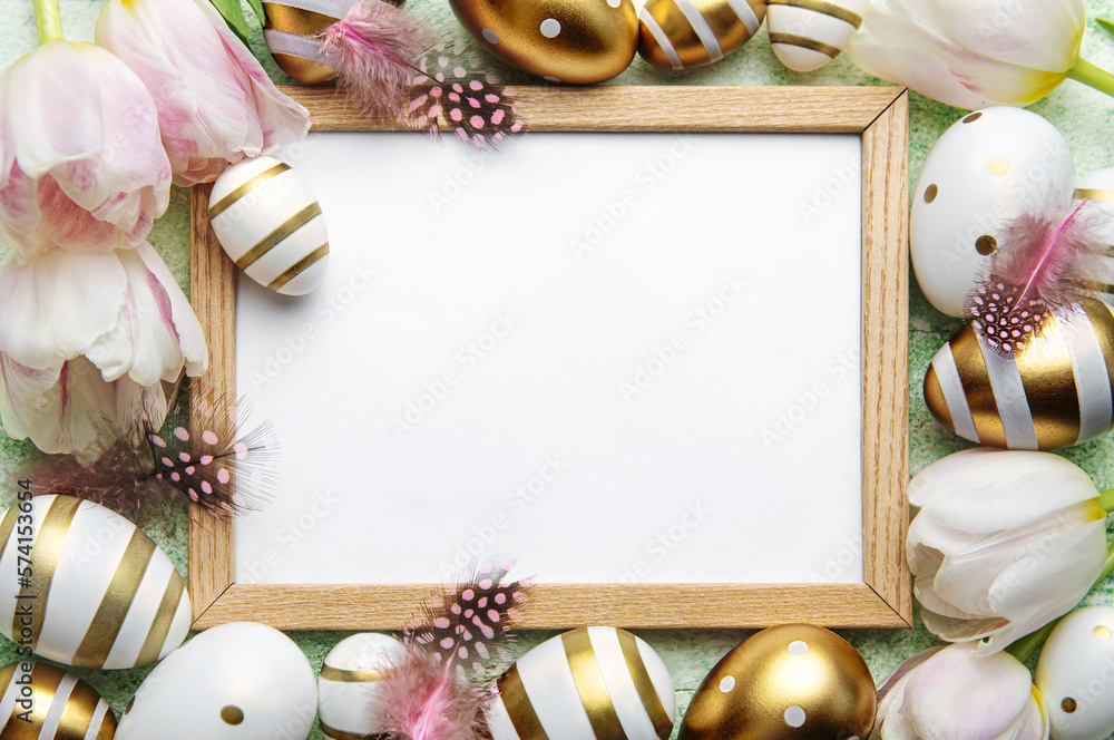 Blank picture frame surrounded by Easter eggs and tulip flowers on green background Blank picture frame surrounded by Easter eggs and tulip flowers on green background