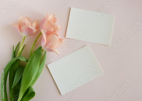 Greeting card mockup and pink tulip flowers on beige background top view flatlay. Blank mock up with copy space. © irenastar