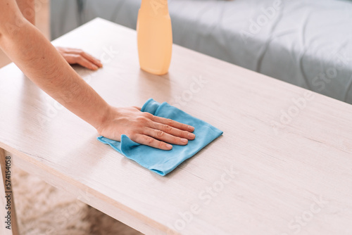 Lady cleaning with a rag the table with detergent.