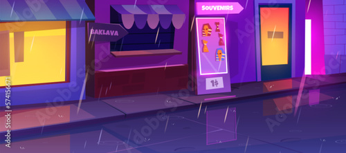 Rain in night city street. Vector cartoon illustration of souvenir shop and local cuisine restaurant facade with illuminated windows, doors and signboards, water puddles on wet road and sidewalk