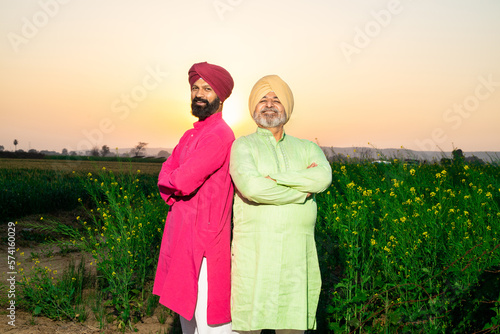 Portrait of happy punjabi srdar farmers wearing kurta and pagdi turban standing together cross arm at agriculture field. Looking at camera. photo