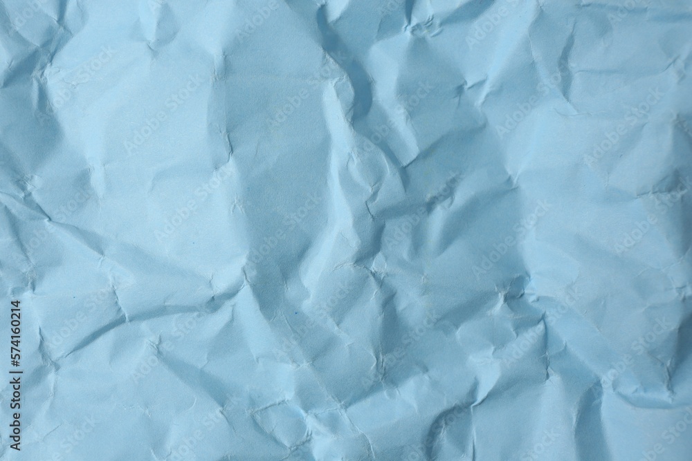Fototapeta premium Sheet of crumpled light blue paper as background, top view