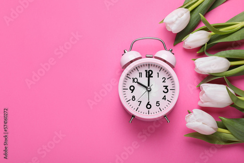 Alarm clock and beautiful tulips on pink background, flat lay with space for text. Spring time