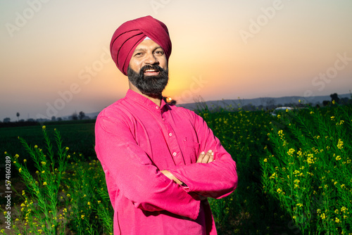 Fotografija Portrait of happy young punjabi sikh farmer standing cross arms turban and kurta at agriculture field