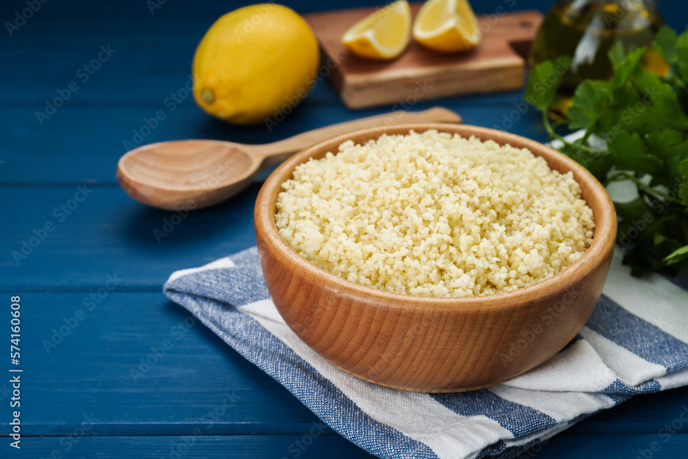 Bowl of tasty couscous on blue wooden table, closeup. Space for text Bowl of tasty couscous on blue wooden table, closeup. Space for text