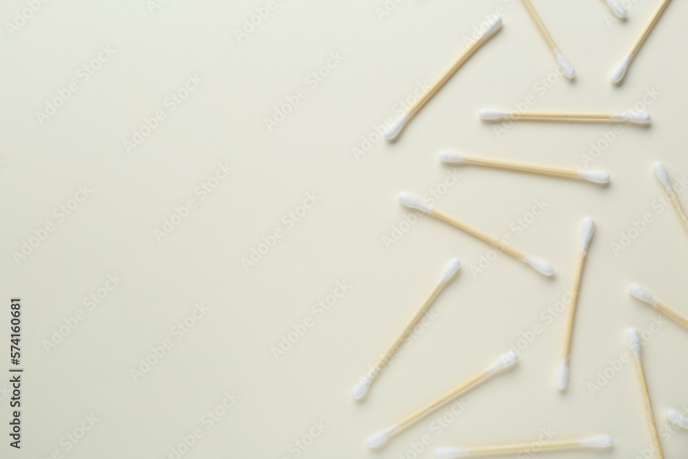 Many wooden cotton buds on beige background, flat lay. Space for text