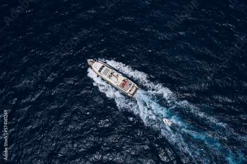 Big white boat moving faster diagonally top view. Large yacht in motion on dark water aerial view.