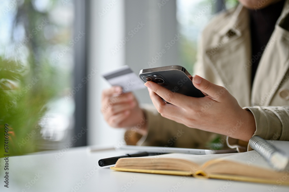 an Asian woman in the coffee shop and using her mobile phone to pay her online bills. an Asian woman in the coffee shop and using her mobile phone to pay her online bills.