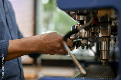 A male barista using portafilter to make an espresso shot with coffee espresso machine