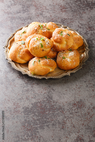 Tasty Garlic knots buns with Parmesan cheese and dried greens closeup on the plate on the table. Vertical