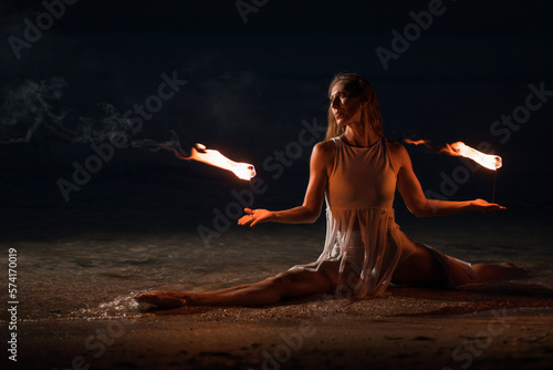 Caucasian woman in a white dress juggles with fireballs in the sea. Fire and water at night. Fire show on the waterfront. High quality FullHD footage. slow motion video
