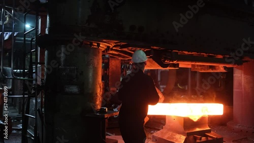 Blacksmith factory. Close-up of robots work. Forging a large hot metal billet with an industrial forging press. Technical equipment of a metal forging plant. Large machines, blacksmiths move and heat