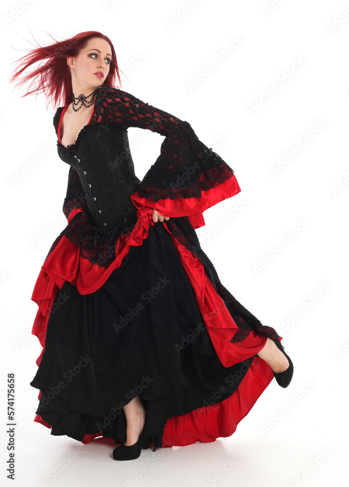 portrait of beautiful red haired woman wearing long black fantasy vampire costume gown, isolated pose on studio background. portrait of beautiful red haired woman wearing long black fantasy vampire costume gown, isolated pose on studio background.