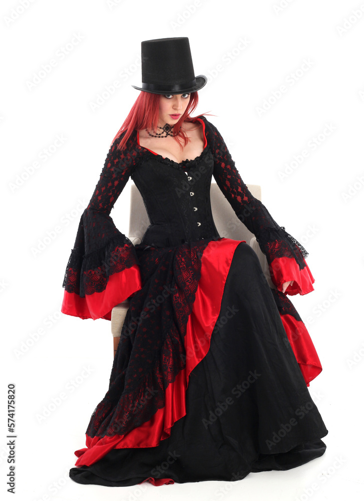 portrait of beautiful red haired woman wearing long black fantasy vampire costume gown, isolated pose on studio background. portrait of beautiful red haired woman wearing long black fantasy vampire costume gown, isolated pose on studio background.