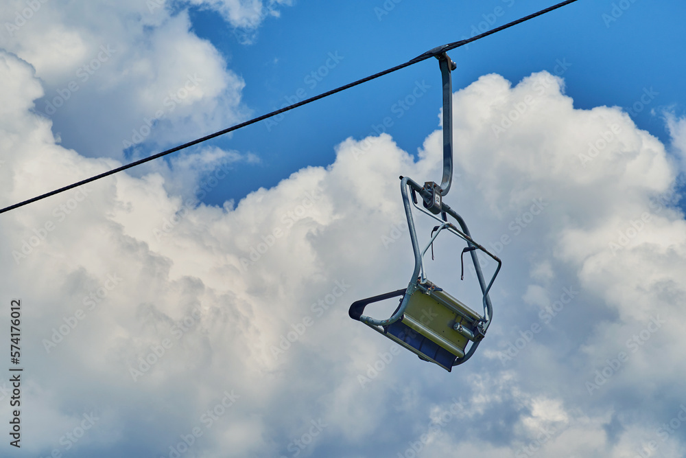 Ski lift chair hanging on a cable against a cloudy sky Ski lift chair hanging on a cable against a cloudy sky