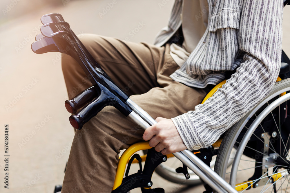 Closeup view, crutches in the hands of a man. A man sits in a