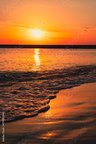 Reflection of sunlight over sea surface at sunset. Orange and gold blue sky. Dramatic Yellow sun coming out of the sea. Majestic summer landscape