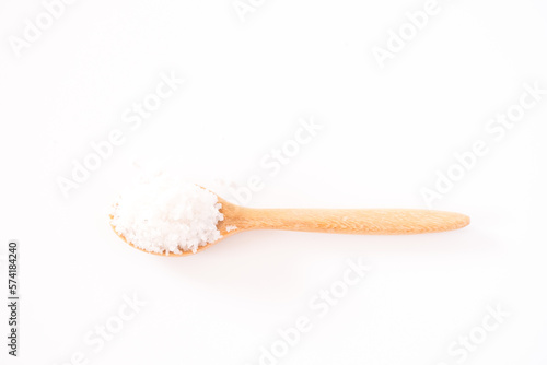 Flower of salt, is a salt that forms as a thin, delicate crust on the surface of seawater in the wooden spoon isolated on white wooden background. Called Fleur de sel in French.