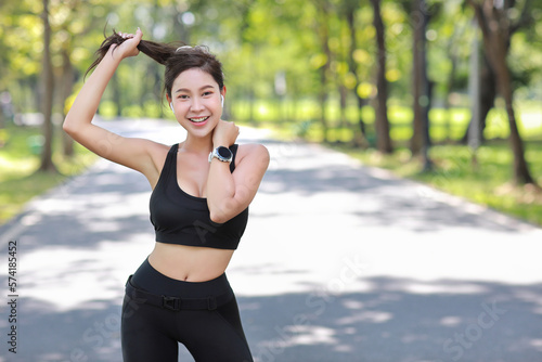 Portrait of happy young asian sportswoman practice yoga stretching and meditation exercise after finish morning run outdoor. Beautiful athlete smile woman listening music under the tree in the park