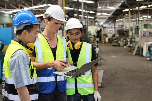 Architect men and worker checking and pointing at heavy industry manufacturing factory with computer. Multiethnic business manager looking in future with warehouse factory building