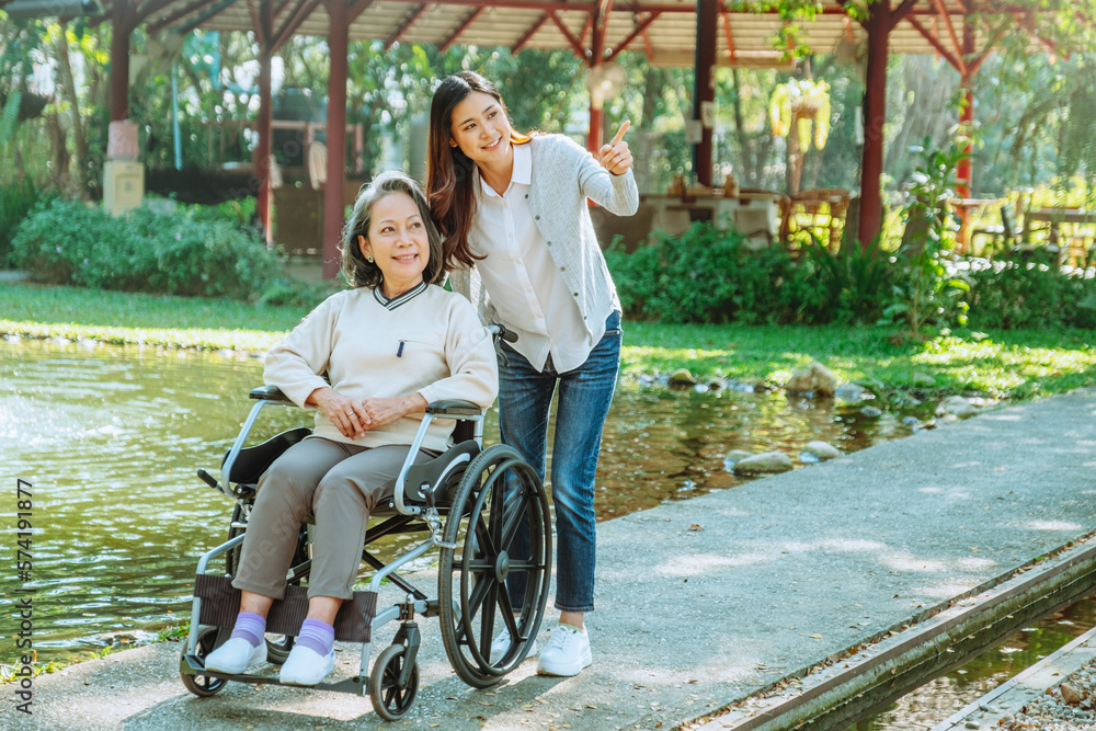 Asian grandmother in wheelchair with daughter is enjoying at the park in the morning