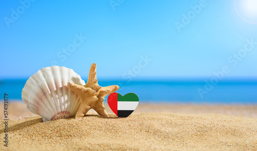 Beautiful beach UAE. Flag of the United Arab Emirates in the shape of a heart and shells on a sandy beach.