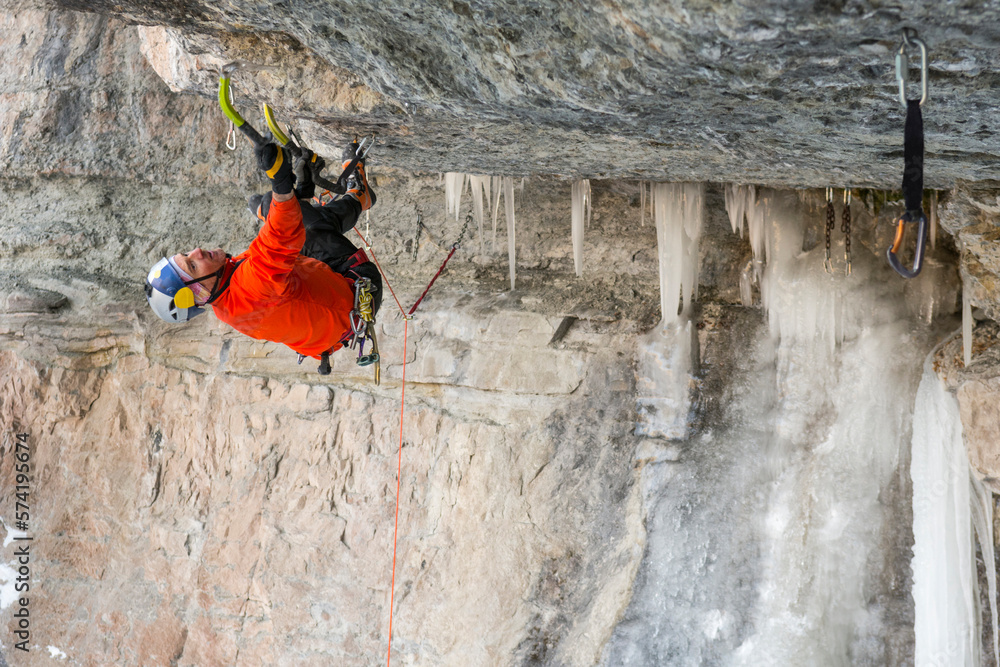Man upside down while ice climbing with twin ice axes, Colorado, USA