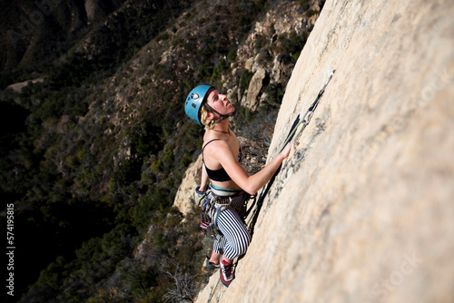 A woman wearing a tank top and striped pants reaches for chalk while climbing The Rapture (5.8) on Lower Gibraltar Rock in Santa Barbara, California.  The Rapture is a very nice an photo