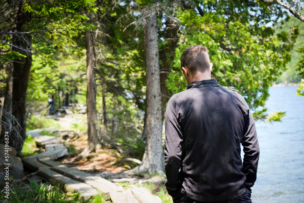 Man walking the split tree boardwalk around Jordan Pond Man walking the split tree boardwalk around Jordan Pond