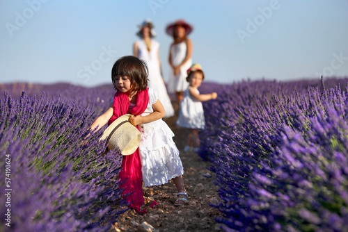 Small Girl Playing With Purple Flowers Growing In Field photo