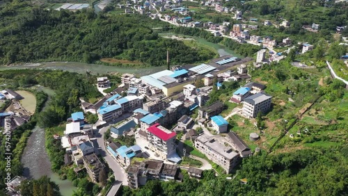 Hills with vegetation and a river with buildings in Hefeng County Hubei Province China. Aerial shot . photo