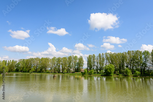 Small lake with a woodmill and an island from Chindiei Park (Parcul Chindiei) in Targoviste, Romania, in a sunny spring day with white clouds and blue sky photo