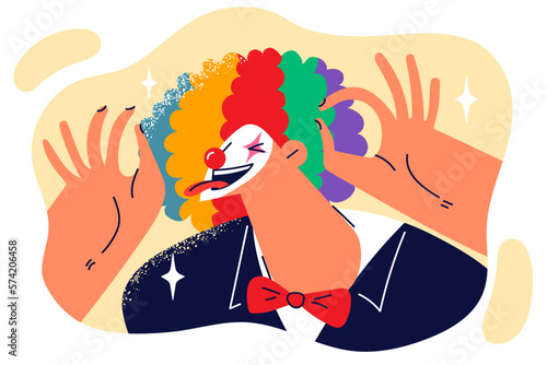 Clown sticks out tongue and makes funny faces to audience laugh at humorous theatrical performance