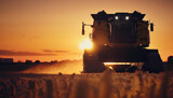 combine harvester working at sunset